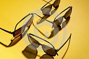 Group of full rim sunglasses is on yellow background.