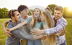 Group of funny, happy, cheerful, excited friends hugging and having fun in the park