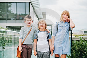 Group of three funny kids wearing backpacks walking back to school