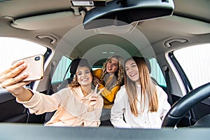 Group of funny women takes a selfie on the road driving a car. Best friends women having fun at vacation