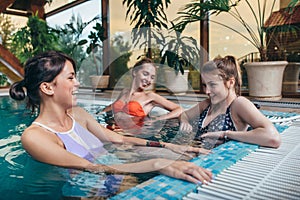 Group of girlfriends having fun in the indoor swimming pool in spa center