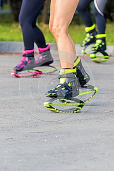 A group of girls dancing in jumpers, in special sneakers on springs in the park on a sunny summer day