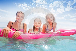 Group of girls on the pink matrass swim in sea