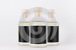 Group glass bottles for cosmetic, perfume, alcohol drink with black label, cork, yellow liquid on white background, mock up.