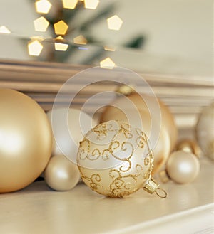 Group of glass Christmas ornaments on living room mantel with reflection of lighted Christmas tree in background. Simple, elegant