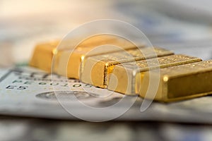 group of gold bar lie on 100 US dollar bills background