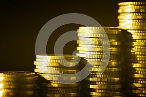 Group of golden coin stacking in vertical row shallow focus with fill in frame with gold coin blur background