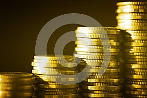 Group of golden coin stacking in vertical row shallow focus with fill in frame with gold coin blur background