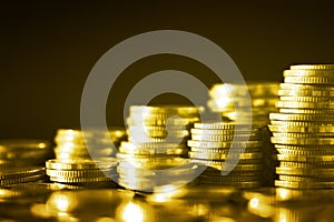 Group of golden coin stacking in vertical row shallow focus with fill in frame with gold coin blur background