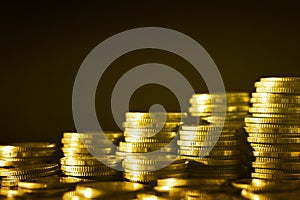 Group of golden coin stacking in vertical row shallow focus with fill in frame with gold coin blur background, rows of coins