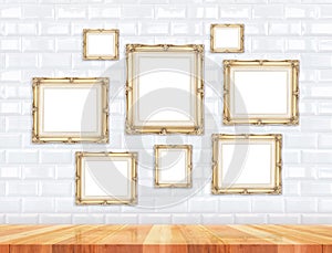 Group of golden Victorian style vintage frames on white tile wall and wood floor,Mock up for adding your photo on picture frames