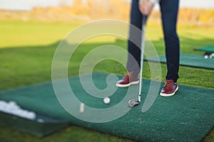 Group of golfers practicing and training golf swing on driving range practice, men playing on golf course, golf ball at golfing