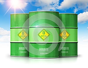 Group of green biofuel drums against blue sky with clouds and sun light