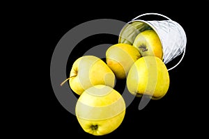 A group of green Granny Smith and golden apples in a white bucket against a dark brown background, copy space for text