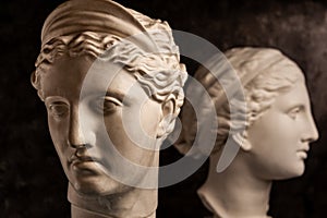 Group gypsum busts of ancient statues human heads for artists on a dark background. Plaster sculptures of antique people