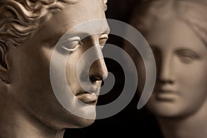 Group gypsum busts of ancient statues human heads for artists on a dark background. Plaster sculptures of antique people