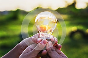 group hand holding lightbulb with sunset. concept idea solar ene