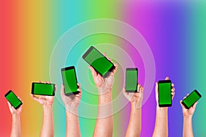 group of hands Raising up Smart phones against colorful background - Hands holding phones