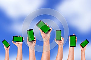 group of hands Raising up Smart phones against green background - Hands holding phones