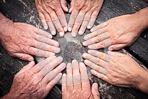 Group of hands touch each other like a seance. Caucasian people women and men. Dark wooden table on background