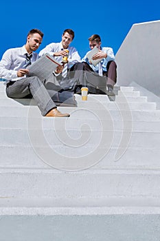 Group of handsome business colleagues sitting on stairs