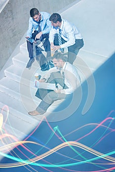 Group of handsome businessman sitting on stairs while preparing business plans during break