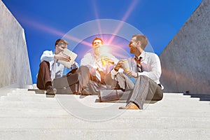 Group of handsome businessman sitting on stairs while talking during break