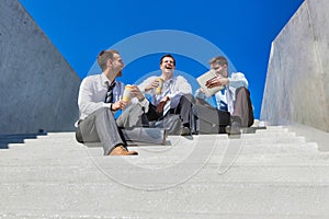 Group of handsome businessman sitting on stairs while talking during break
