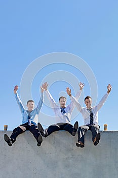 Group of handsome businessmen sitting while having fun in office rooftop