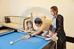 Group of happiness asian family father, mother, son and daughter playing billiard or snooker on blue pool table with happy smiling