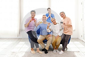 Group of happy Asian elderly senior people standing and sitting on the sofa while holding credit cards with a woman nurse.