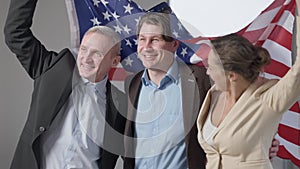 Group of happy business people with American flag looking away smiling. Excited successful men and woman rejoicing