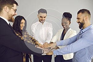 Group of happy business people demonstrating teamwork and putting their hands together