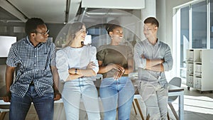 Group of happy businesspeople standing and talking together in an office. Content business professionals standing with