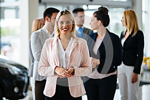 Group of happy car sales consultants working inside vehicle showroom