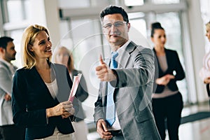 Group of happy car sales consultants working inside vehicle showroom