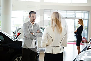 Group of happy car sales consultants working inside vehicle showroom