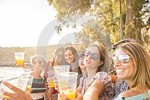 Group of happy and cheerful young women friends enjoy and celebrate social life together - people toasting and clinking outdoor