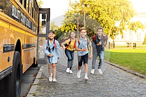 Group of happy children with backpacks running from school bus