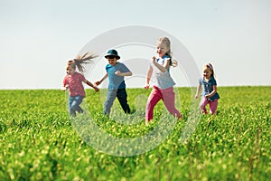 A group of happy children of boys and girls run in the Park on the grass on a Sunny summer day . The concept of ethnic friendship