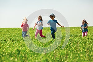 A group of happy children of boys and girls run in the Park on the grass on a Sunny summer day . The concept of ethnic friendship