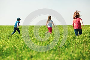 A group of happy children of boys and girls run in the Park on the grass on a Sunny summer day . The concept of ethnic friendship