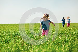 A group of happy children of boys and girls run in the Park on the grass on a Sunny summer day . The concept of ethnic friendship