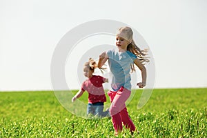 A group of happy children of boys and girls run in the Park on the grass on a Sunny summer day . The concept of ethnic friendship