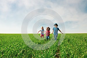 A group of happy children of boys and girls run in the Park on the grass on a Sunny summer day . The concept of ethnic friendship