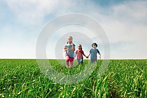 A group of happy children of boys and girls run in the Park on the grass on a Sunny summer day . The concept of ethnic friendship