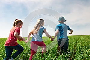 A group of happy children of boys and girls run in the Park on the grass on a Sunny summer day . The concept of ethnic friendship