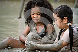 Group of happy children girl playing in wet mud puddle on summer day in rainy season