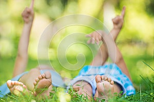 Group of happy children lying on green grass and pointing
