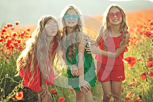 Group of happy children playing outdoors. Children have fun in the spring park. Girls run in the field with poppies.